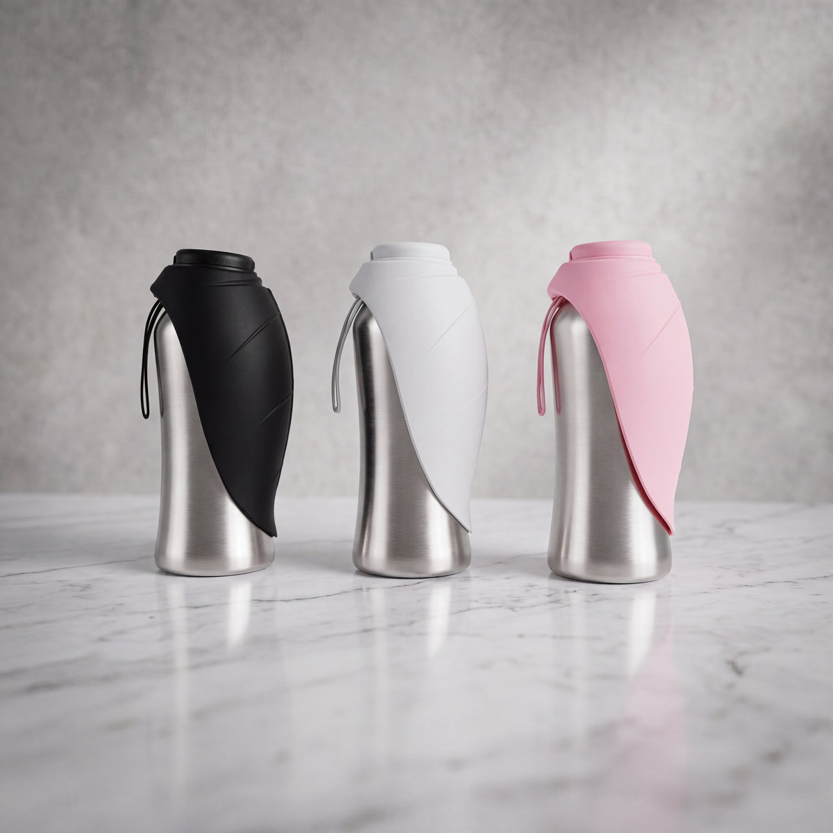 Gamme de trois gourdes isothermes pour chien de 750ml en inox (coloris noir, blanc et rose) debout avec l'écuelle en silicone refermée autour de la bouteille.